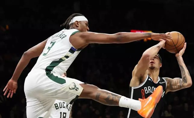 Brooklyn Nets forward Michael Porter Jr. gets Milwaukee Bucks center Myles Turner (3) up in the air while he drives to the basket during the first half of an NBA basketball game, Sunday, Dec. 14, 2025, in New York. (AP Photo/Heather Khalifa)