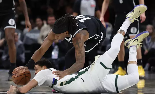 Milwaukee Bucks guard Ryan Rollins and Brooklyn Nets guard Terance Mann (14) battle for a loose ball during the first half of an NBA basketball game, Sunday, Dec. 14, 2025, in New York. (AP Photo/Heather Khalifa)
