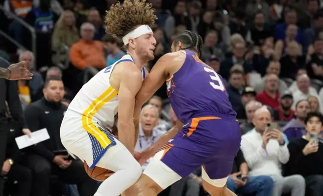 Golden State Warriors guard Brandin Podziemski, left, collides with Phoenix Suns forward Dillon Brooks (3) as they go after a loose ball during the first half of an NBA basketball game Thursday, Dec. 18, 2025, in Phoenix. (AP Photo/Ross D. Franklin)