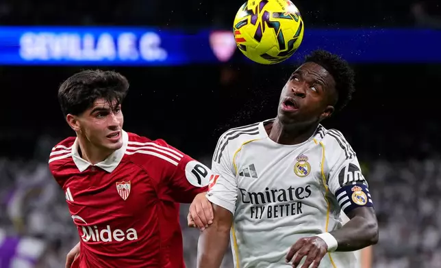 Real Madrid's Vinicius Junior, right looks to control the ball under pressure from Sevilla's Juanlu Sanchez during the Spanish La Liga soccer match between Real Madrid and Sevilla in Madrid, Spain, Saturday, Dec. 20, 2025. (AP Photo/Manu Fernandez)