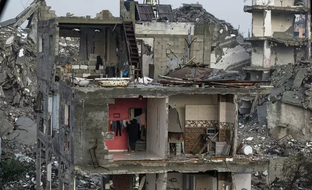 A Palestinian woman hangs laundry in a wallless, damaged apartment in Gaza City, Monday, Dec. 15, 2025. (AP Photo/Jehad Alshrafi)