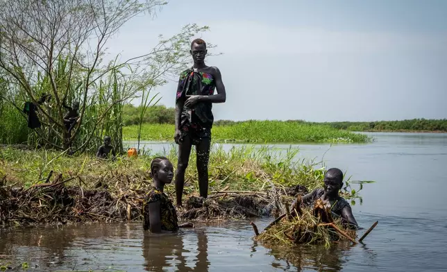 Ayen Deng Duot, right, and her family reinforce their island with vegetation and mud from the swamp to prevent their home from being flooded along the Nile River in Akuak, South Sudan, on 8 November 2025. (AP Photo/Florence Miettaux)