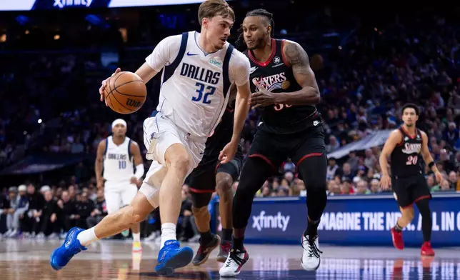 Dallas Mavericks' Cooper Flagg, center left, drives to the basket against Philadelphia 76ers' Jabari Walker, center right, during the first half of an NBA basketball game, Saturday, Dec. 20, 2025, in Philadelphia. (AP Photo/Chris Szagola)