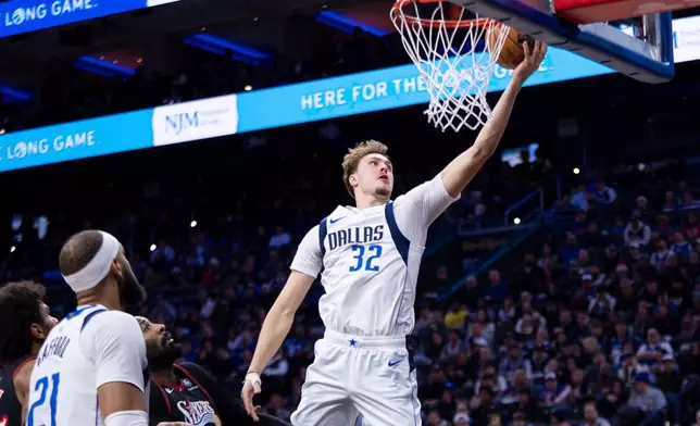 Dallas Mavericks' Cooper Flagg, right, goes up to shoot as Philadelphia 76ers' Andre Drummond, second from right, watches during the first half of an NBA basketball game, Saturday, Dec. 20, 2025, in Philadelphia. (AP Photo/Chris Szagola)