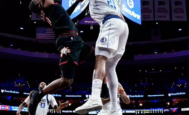 Dallas Mavericks' Daniel Gafford, top right, blocks a shot by Philadelphia 76ers' Tyrese Maxey, top left, during the first half of an NBA basketball game, Saturday, Dec. 20, 2025, in Philadelphia. (AP Photo/Chris Szagola)