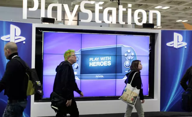 FILE- Attendees walking past the Sony PlayStation PS Vita console on display in the Sony PlayStation booth at the Game Developers Conference in San Francisco on March 8, 2012. (AP Photo/Paul Sakuma, File)