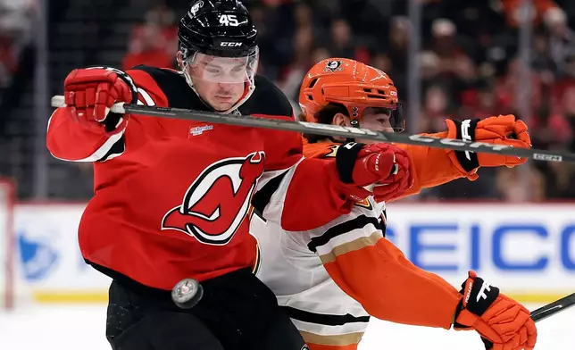 New Jersey Devils defenseman Colton White (45) collides with Anaheim Ducks center Ryan Poehling chasing down a puck during the first period of an NHL hockey game Saturday, Dec. 13, 2025, in Newark, N.J. (AP Photo/Adam Hunger)