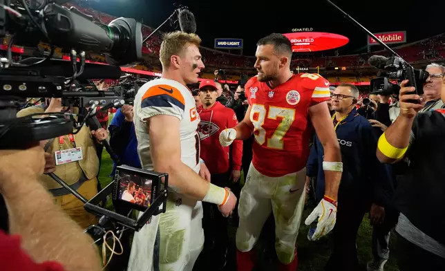 Kansas City Chiefs tight end Travis Kelce, right, talks to Denver Broncos quarterback Bo Nix following an NFL football game Thursday, Dec. 25, 2025, in Kansas City. (AP Photo/Charlie Riedel)