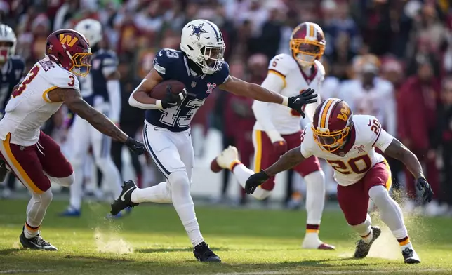 Dallas Cowboys running back Malik Davis (43) runs with the ball as Washington Commanders safety Quan Martin (20) and safety Will Harris (3) defend during the first half an NFL football game Thursday, Dec. 25, 2025, in Landover, Md. (AP Photo/Stephanie Scarbrough)