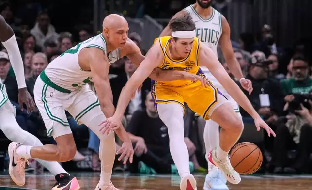 Boston Celtics guard Jordan Walsh, left, battles for a loose ball against Los Angeles Lakers guard Austin Reaves, right, during the first half of an NBA basketball game, Friday, Dec. 5, 2025, in Boston. (AP Photo/Charles Krupa)