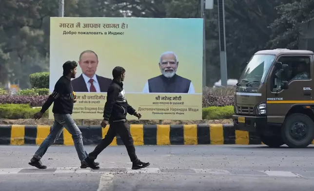 Men walk past a billboard with portraits of Indian Prime Minister Narendra Modi, right, and Russian President Vladimir Putin, hours before the scheduled arrival of the latter in New Delhi, India, Thursday, Dec. 4, 2025. (AP Photo)