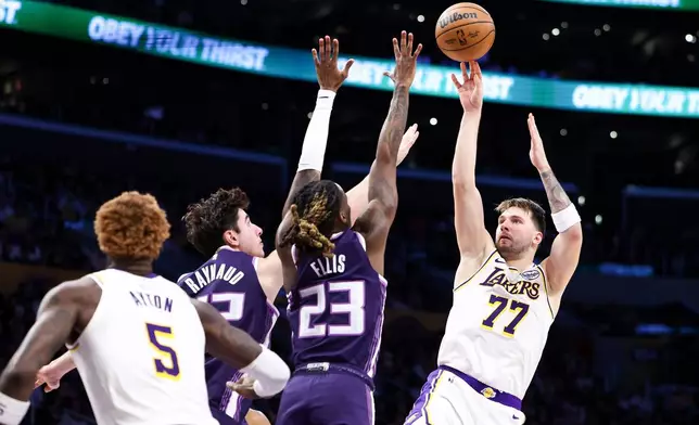 Los Angeles Lakers guard Luka Doncic (77) passes against Sacramento Kings center Maxime Raynaud, second from left, and guard Keon Ellis (23), as center Deandre Ayton (5) watches during the first half of an NBA basketball game, Sunday, Dec. 28, 2025, in Los Angeles. (AP Photo/Jessie Alcheh)