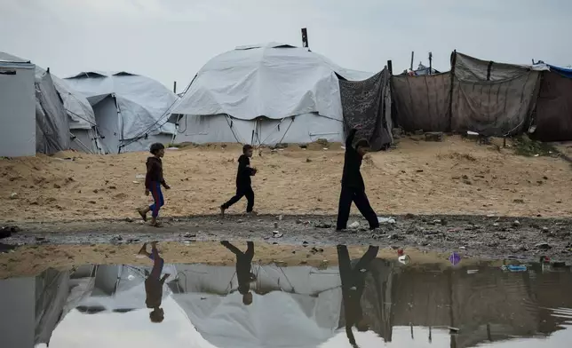 Displaced Palestinian children walk through a tent camp after stormy weather in Gaza City Wednesday, Dec. 10, 2025. (AP Photo/Jehad Alshrafi)