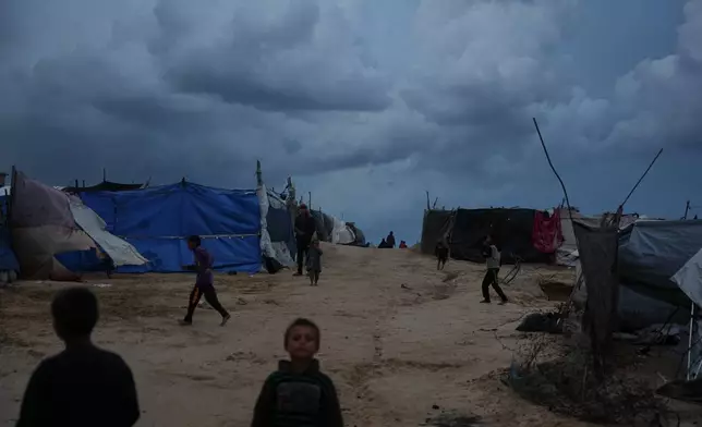 Displaced Palestinian children play beside a makeshift tent camp where they take shelter in Zawaida, in the central Gaza Strip, Wednesday, Dec. 10, 2025. (AP Photo/Abdel Kareem Hana)