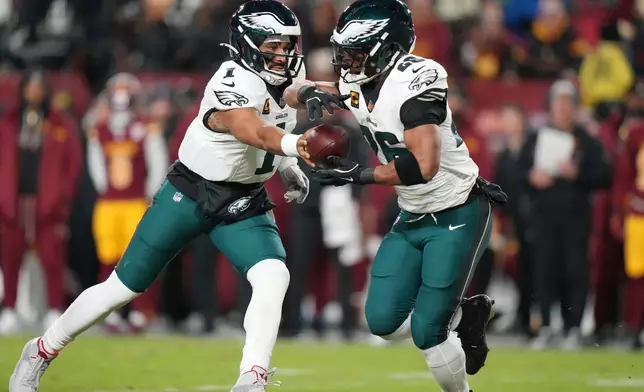 Philadelphia Eagles quarterback Jalen Hurts (1) hands off to running back Saquon Barkley (26) during the first half of an NFL football game against the Washington Commanders, Saturday, Dec. 20, 2025, in Landover, Md. (AP Photo/Stephanie Scarbrough)