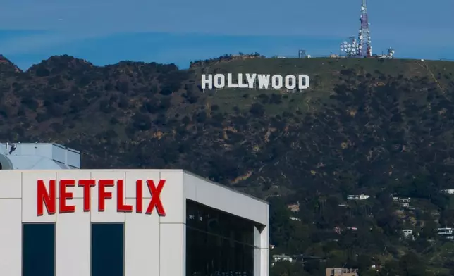 A Netflix sign is displayed atop a building in Los Angeles, Thursday, Dec. 18, 2025, with the Hollywood sign in the distance. (AP Photo/Jae C. Hong)