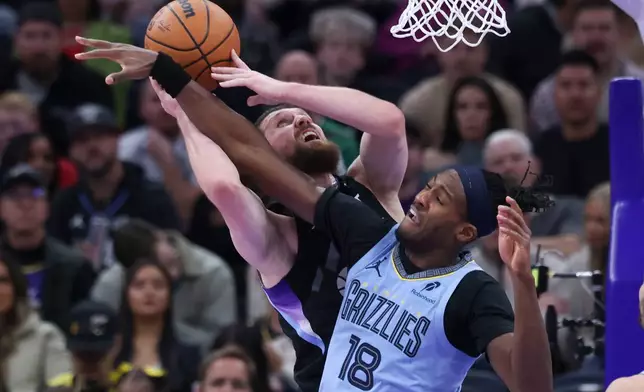 Utah Jazz guard Svi Mykhailiuk, left, is fouled by Memphis Grizzlies forward Olivier-Maxence Prosper (18) while going to the basket during the first half of an NBA basketball game, Tuesday, Dec. 23, 2025, in Salt Lake City. (AP Photo/Rob Gray)