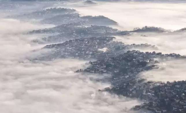 An aerial view of houses blanketed by a dense layer of fog in Sarajevo, Bosnia, Thursday, Dec. 18, 2025. (AP Photo/Armin Durgut)
