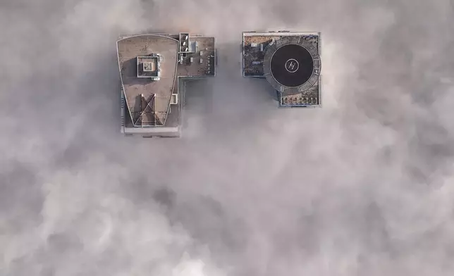 An aerial view of buildings peaking through a dense layer of fog in Sarajevo, Bosnia, Thursday, Dec. 18, 2025. (AP Photo/Armin Durgut)