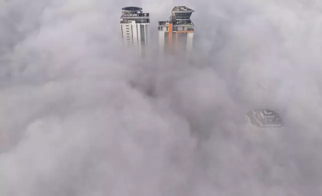 An aerial view of buildings peaking through a dense layer of fog in Sarajevo, Bosnia, Thursday, Dec. 18, 2025. (AP Photo/Armin Durgut)