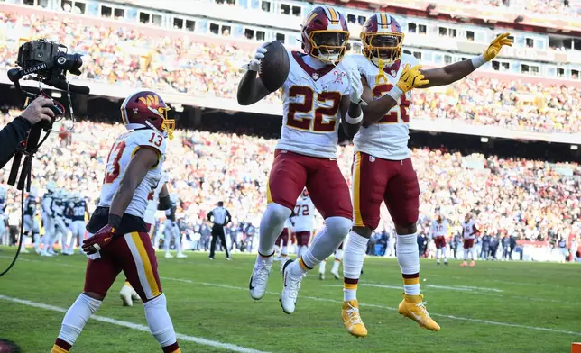 Washington Commanders running back Jacory Croskey-Merritt (22) is congratulated by teammates running back Jeremy McNichols and wide receiver Treylon Burks (13) after scoring during the first half an NFL football game against the Dallas Cowboys Thursday, Dec. 25, 2025, in Landover, Md. (AP Photo/Nick Wass)
