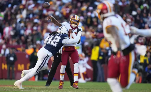 Washington Commanders quarterback Josh Johnson (14) is hit as he throws by Dallas Cowboys defensive end Jadeveon Clowney (42) during the second half an NFL football game Thursday, Dec. 25, 2025, in Landover, Md. (AP Photo/Stephanie Scarbrough)
