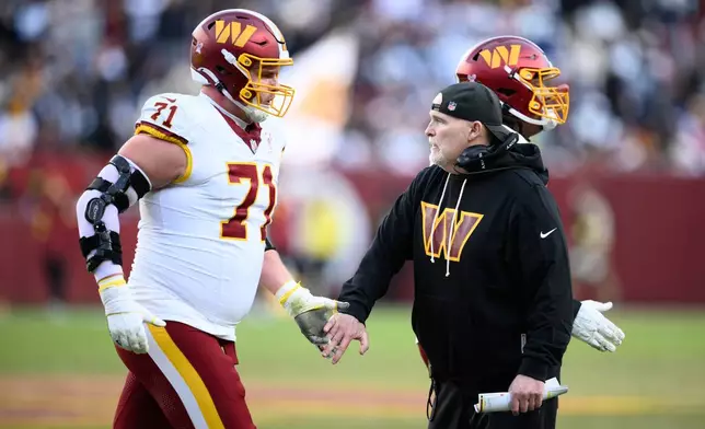 Washington Commanders head coach Dan Quinn shakes hands with Andrew Wylie (71) during the second half an NFL football game Thursday, Dec. 25, 2025, in Landover, Md. (AP Photo/Nick Wass)