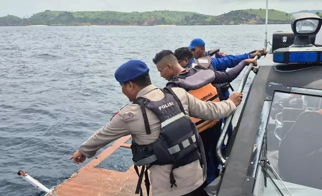 In this photo released by the Indonesian National Search and Rescue Agency (BASARNAS) on Saturday, Dec. 27, 2025, rescuers examine a debris believed to be from a tour boat that sank, near Padar Island within Komodo National Park, Indonesia. (BASARNAS via AP)