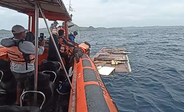 In this photo released by the Indonesian National Search and Rescue Agency (BASARNAS) on Saturday, Dec. 27, 2025, rescuers examine a debris believed to be a part of a tour boat that sank, near Padar Island within Komodo National Park, Indonesia. (BASARNAS via AP)