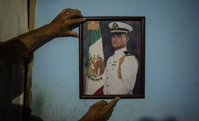 Eduardo Castillo shows a portrait of his son Lt. Luis Enrique Castillo, a victim of a Mexican Navy plane crash off the Texas coast, at the family house in El Pantano, Veracruz state, Mexico, Tuesday, Dec. 23, 2025. (AP Photo/Felix Marquez)