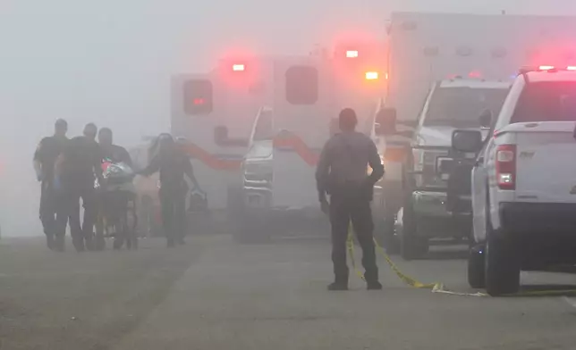 Emergency personnel rush a victim of a small plane crash to an awaiting ambulance, Monday, Dec. 22, 2025, near the Galveston causeway, near Galveston, Texas. (Jennifer Reynolds/The Galveston County Daily News via AP)