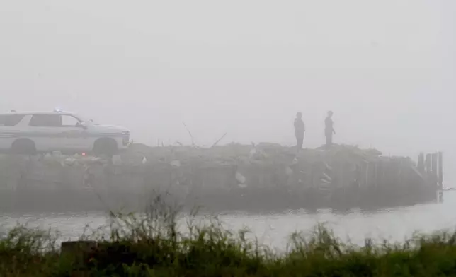Galveston Police officers watch the water on Galveston Bay west of the Galveston causeway, Monday, Dec. 22, 2025, near Galveston, Texas, as emergency personnel search for a small airplane that went down in the bay in heavy fog. (Jennifer Reynolds/The Galveston County Daily News via AP)