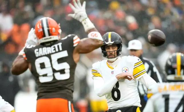 Pittsburgh Steelers quarterback Aaron Rodgers (8) throws a pass around Cleveland Browns defensive end Myles Garrett (95) during the first half of an NFL football game, Sunday, Dec. 28, 2025, in Cleveland. (AP Photo/Sue Ogrocki)