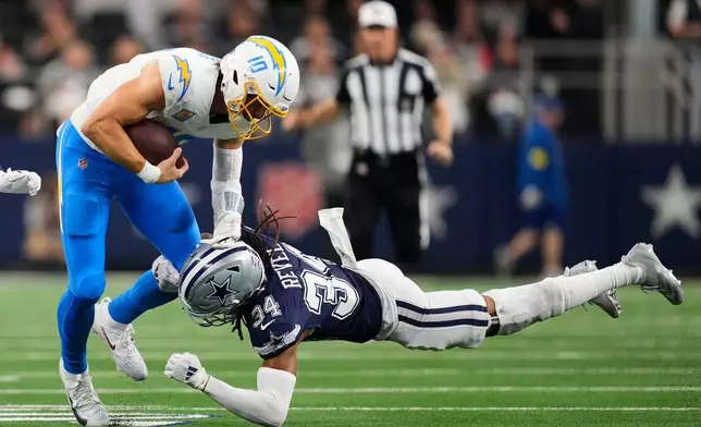 Los Angeles Chargers quarterback Justin Herbert (10) is tackled by Dallas Cowboys cornerback Shavon Revel during the second half of an NFL football game Sunday, Dec. 21, 2025, in Arlington, Texas. (AP Photo/Tony Gutierrez)