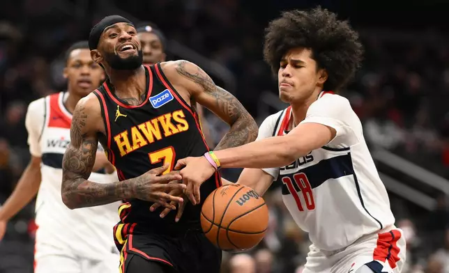 Washington Wizards forward Kyshawn George (18) and Atlanta Hawks guard Nickeil Alexander-Walker, left, battle for the ball during the second half of an NBA basketball game, Saturday, Dec. 6, 2025, in Washington. (AP Photo/Nick Wass)