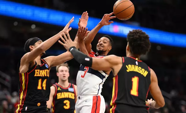 Washington Wizards guard CJ McCollum (3) passes the ball against Atlanta Hawks forward Asa Newell (14), forward Jalen Johnson (1) and guard Luke Kennard (3) during the first half of an NBA basketball game, Saturday, Dec. 6, 2025, in Washington. (AP Photo/Nick Wass)