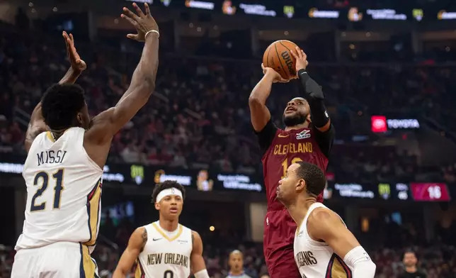 Cleveland Cavaliers' Darius Garland (10) shoots as New Orleans Pelicans' Yves Missi (21) defends and Jeremiah Fears (0) and Bryce McGowens, right, look on during the first half of an NBA basketball game in Cleveland, Tuesday, Dec. 23, 2025. (AP Photo/Phil Long)