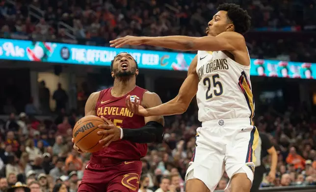 Cleveland Cavaliers' Donovan Mitchell, left, drives against New Orleans Pelicans' Trey Murphy III (25) during the first half of an NBA basketball game in Cleveland, Tuesday, Dec. 23, 2025. (AP Photo/Phil Long)