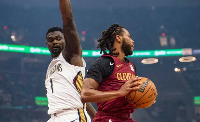 Cleveland Cavaliers' Darius Garland, right, keeps the ball from New Orleans Pelicans' Zion Williamson (1) during the first half of an NBA basketball game in Cleveland, Tuesday, Dec. 23, 2025. (AP Photo/Phil Long)