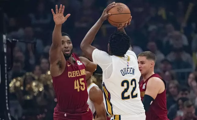 Cleveland Cavaliers' Donovan Mitchell (45) defends as New Orleans Pelicans' Derik Queen (22) shoots during the first half of an NBA basketball game in Cleveland, Tuesday, Dec. 23, 2025. (AP Photo/Phil Long)