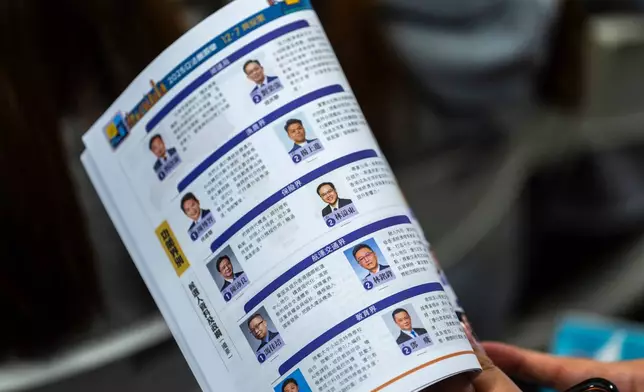 People look at a candidate brochure of the Hong Kong Legislative Council General Election at a forum in Hong Kong on Wednesday, Dec. 3, 2025. (AP Photo/Chan Long Hei)
