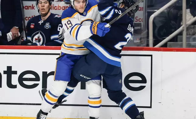 Winnipeg Jets' Dylan DeMelo (2) and Buffalo Sabres' Peyton Krebs (19) collide during first-period NHL hockey game action in Winnipeg, Manitoba, Friday, Dec. 5, 2025. (John Woods/The Canadian Press via AP)