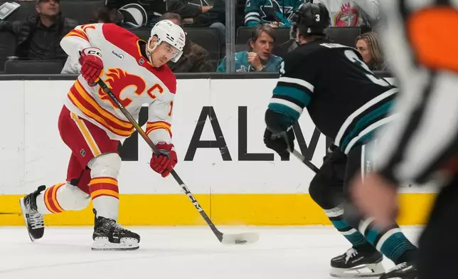 Calgary Flames center Mikael Backlund, left, shoots the puck against San Jose Sharks defenseman John Klingberg during the second period of an NHL hockey game in San Jose, Calif., Tuesday, Dec. 16, 2025. (AP Photo/Jeff Chiu)
