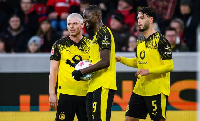 Dortmund's scorer Ramy Bensebaini, right, and his teammates celebrate the opening goal during the German Bundesliga soccer match between SC Freiburg and Borussia Dortmund in Freiburg, Germany, Sunday, Dec. 14, 2025. (Tom Weller/dpa via AP)