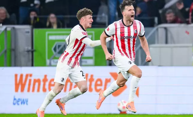 Freiburg's Lucas Hoeler, right, celebrates after scoring his side's first goal during the German Bundesliga soccer match between SC Freiburg and Borussia Dortmund in Freiburg, Germany, Sunday, Dec. 14, 2025. (Tom Weller/dpa via AP)