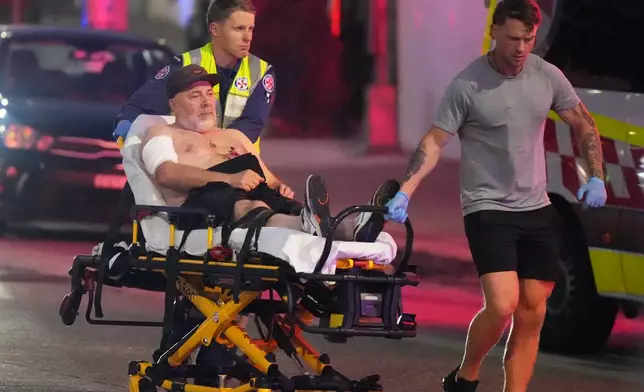 Emergency workers transport a person on a stretcher after a reported shooting at Bondi Beach in Sydney, Sunday, Dec. 14, 2025. (AP Photo/Mark Baker)