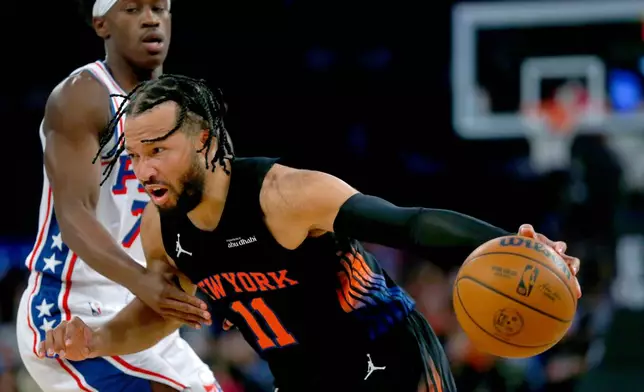 New York Knicks guard Jalen Brunson, right, dribbles around Philadelphia 76ers guard VJ Edgecombe during the first half of an NBA basketball game, Friday, Dec. 19, 2025, in New York. (AP Photo/John Munson)