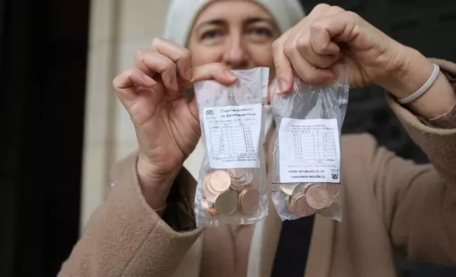 A woman poses as she holds new euro coins with Bulgarian symbols in Sofia in front of Bulgarian National Bank, Saturday Dec. 27, 2025. (AP Photo/Valentina Petrova)