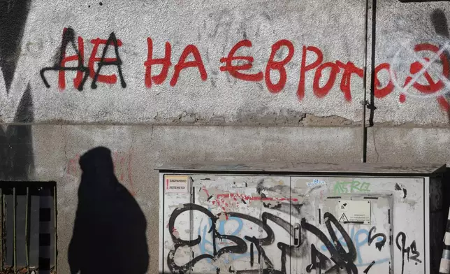 The shadow of a person seen next to graffiti reading "No to the euro" altered to "Yes to the euro" in Sofia, Monday, Dec. 29, 2025. (AP Photo/Valentina Petrova)