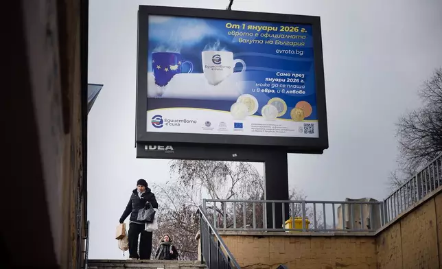 A woman passes by a billboard displaying Eurozone information campaign in Sofia, Saturday, Dec. 27, 2025. (AP Photo/Valentina Petrova)
